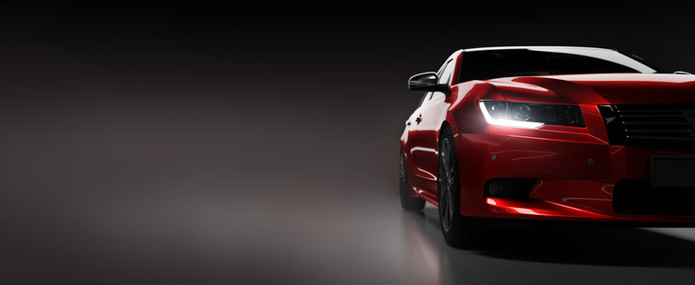 A half visible red car in a dark room